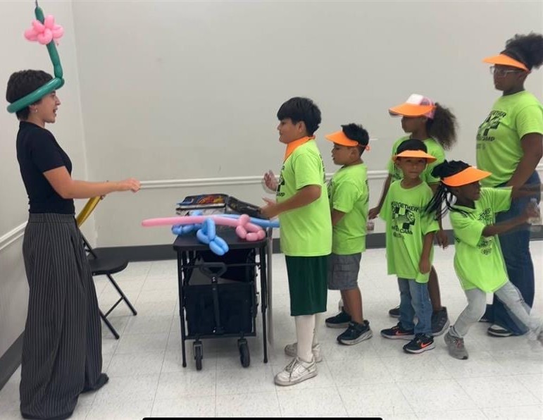 Kids lined up for balloon twisting at a Texas summer camp