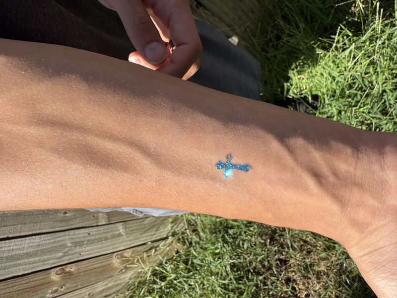 Blue glitter tattoo design on a wrist at a Texas event