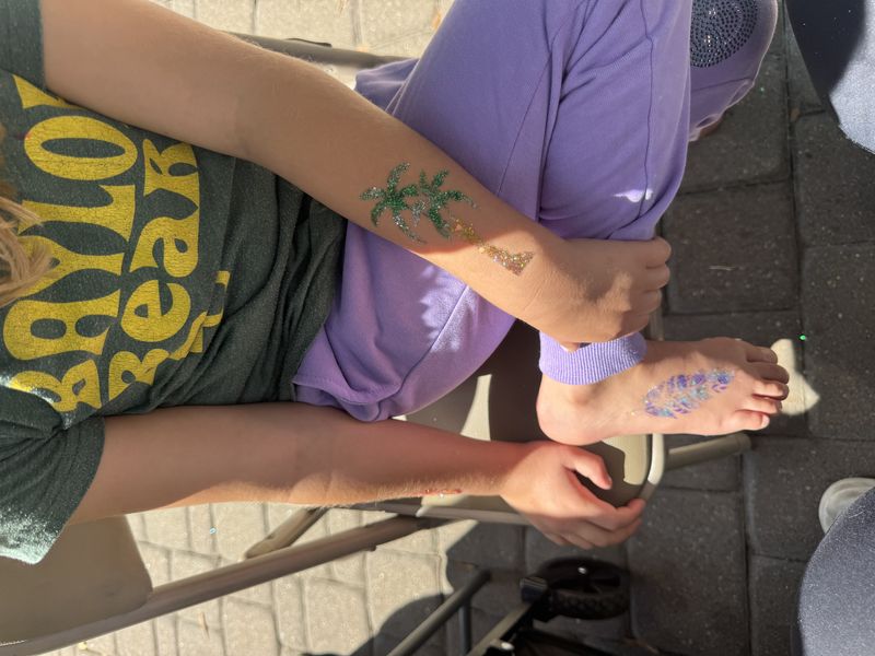Palm tree and feather glitter tattoo designs at a Texas party