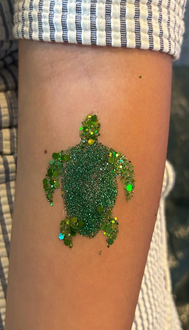 Green glitter turtle tattoo on a child at a Texas party